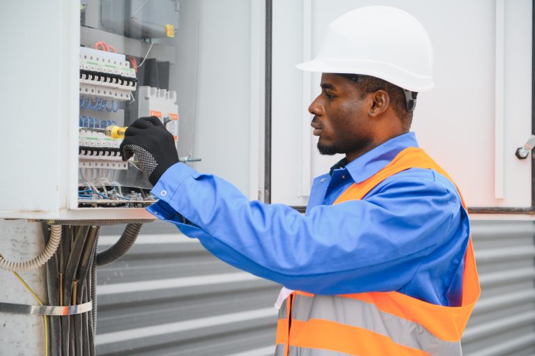 A male african american electrician works in a switchboard.