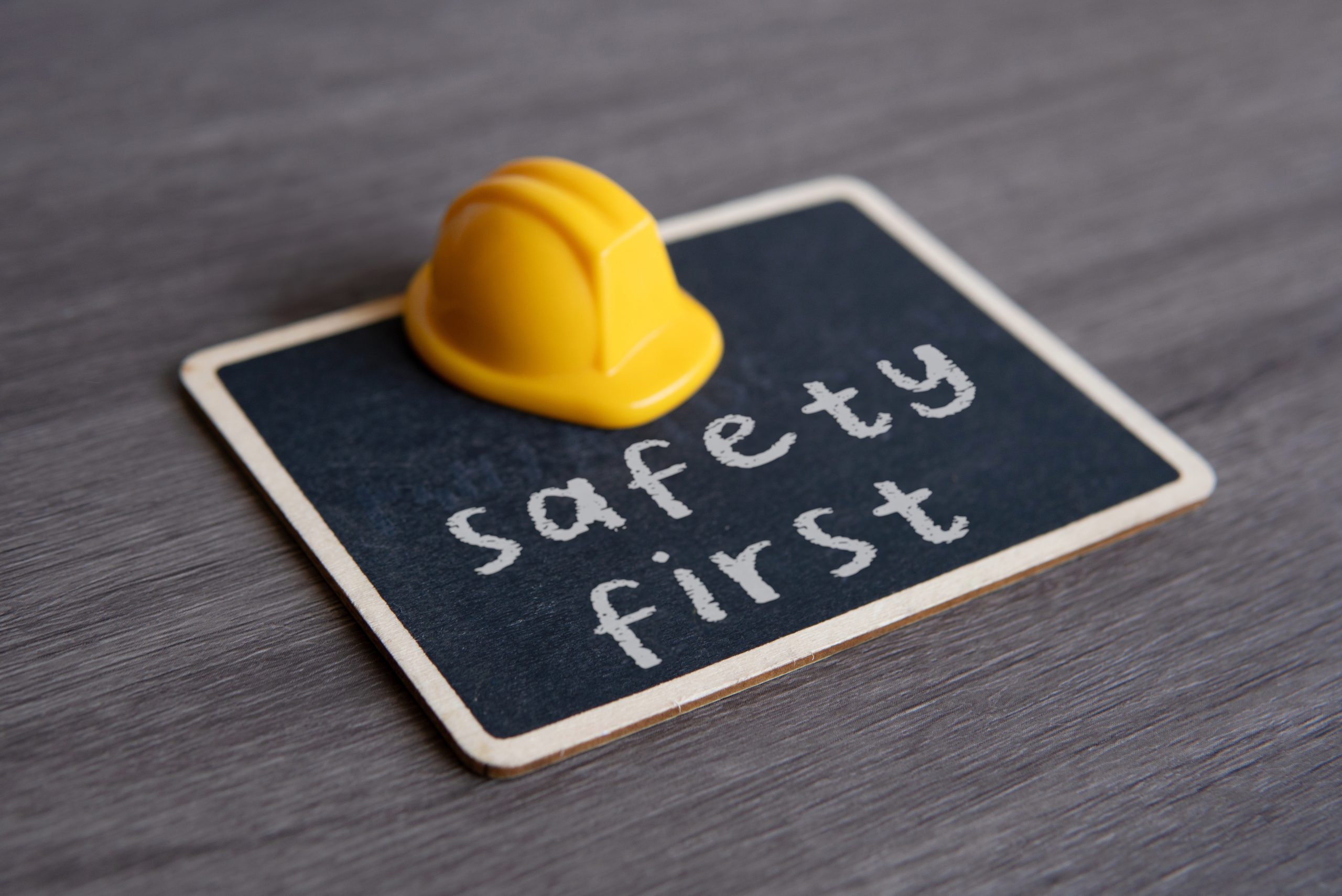 Yellow hard hat and chalkboard with text SAFETY FIRST.