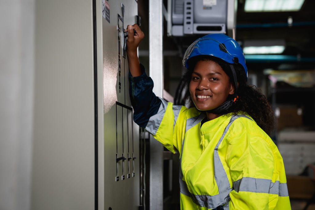 Technician in a yellow and blue safety vest is working on a panel